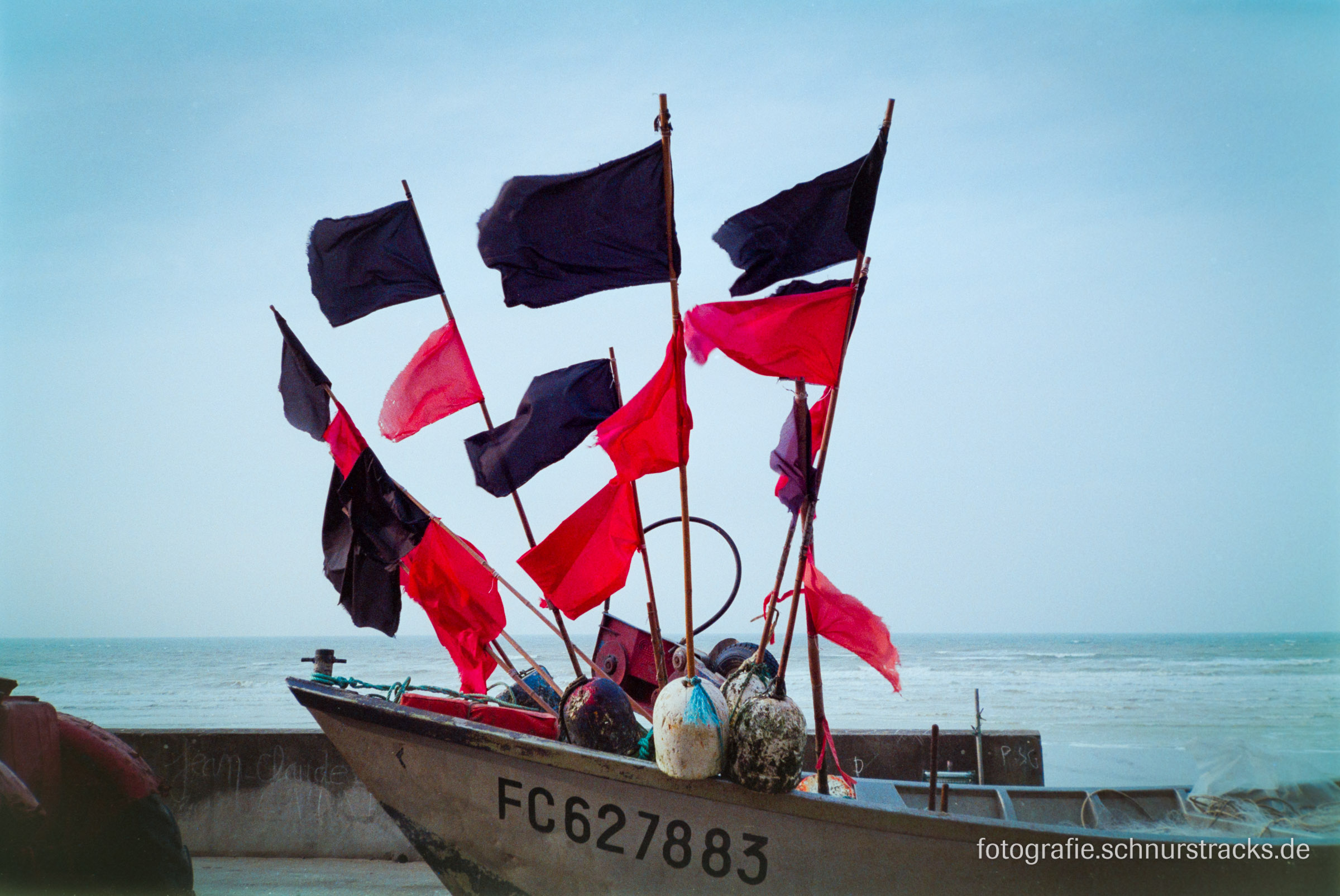 Schwarze und rote Fahnen auf einem Fischerboot in der Normandie 2003 #5185
